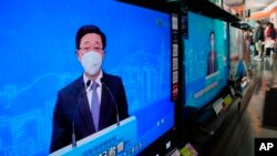 TV screens show Hong Kong's number two official, John Lee, speaking during an online press conference to announce his candidacy for the election of Hong Kong chief executive, in Hong Kong, April 9, 2022.