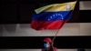 ARCHIVO - Un simpatizante del gobernante Partido Socialista Unido de Venezuela, ondea una bandera durante una conferencia de prensa de Jorge Arreaza, candidato del partido a la gubernatura del estado de Barinas, derrotado en las elecciones para gobernador, el 10 de enero de 2022.