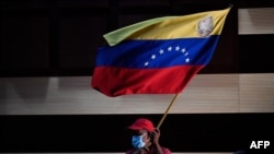 Un simpatizante del gobernante Partido Socialista Unido de Venezuela (PSUV), ondea una bandera nacional venezolana durante una conferencia de prensa de Jorge Arreaza, el 10 de enero de 2022.