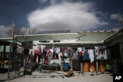 FILE - A child rides a toy car under a clothesline in a courtyard of the Good Samaritan shelter in Juarez, Mexico, March 29, 2022.