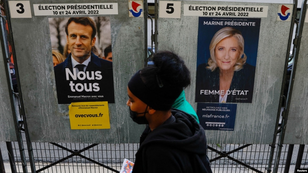 Orang-orang berjalan melewati poster kampanye resmi kandidat pemilihan presiden Prancis Marine le Pen, pemimpin partai sayap kanan Nasional Rally (Rassemblement National) Prancis, dan Presiden Prancis Emmanuel Macron. (Foto: Reuters)