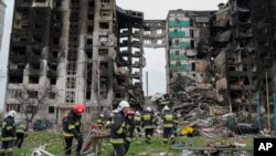 Trabajadores de emergencia transportan escombros de un edificio de varios pisos destruido en un ataque aéreo ruso al comienzo de la guerra entre Rusia y Ucrania en Borodyanka, cerca de Kiev, Ucrania, el sábado 9 de abril de 2022. (Foto AP/Efrem Lukatsky)