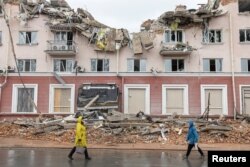Women walk along a street in front of the destroyed Hotel Ukraine, as Russia's invasion of Ukraine continues, in Chernihiv, Ukraine, April 6, 2022.