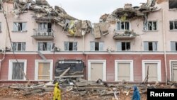 Dua perempuan di depan Hotel Ukraina yang hancur, sementara invasi Rusia terus berlangsung, di Chernihiv, Ukraina. 6 April 2022. 