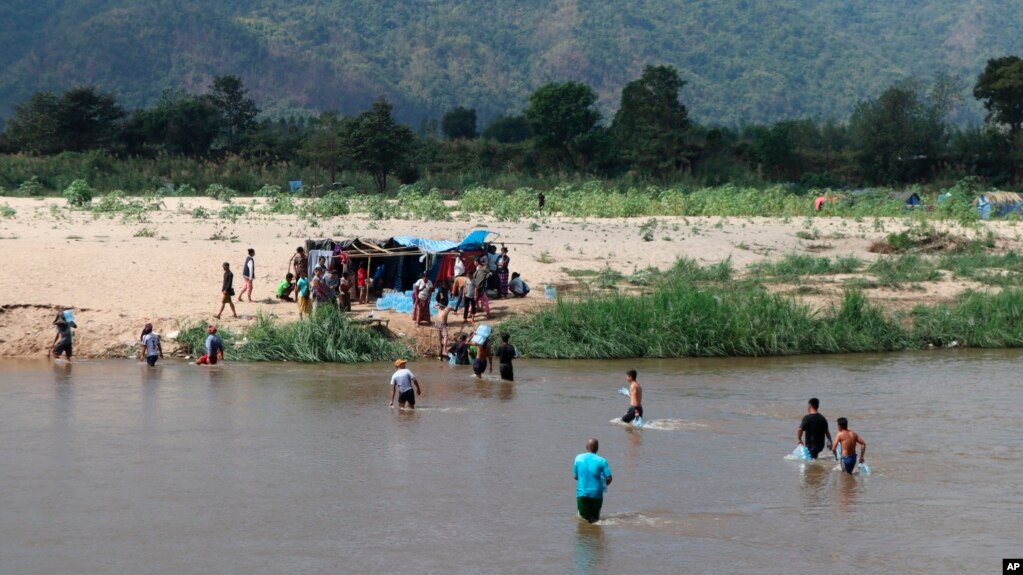 Displaced people from Myanmar wade across the river from Thailand into Myanmar, as seen from Mae Sot, Thailand, Feb. 7, 2022.