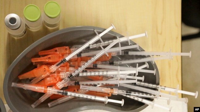 FILE - Medical personnel reach for pre-loaded syringes as they vaccinate students at KIPP Believe Charter School in New Orleans, Tuesday, Jan. 25, 2022. (AP Photo/Ted Jackson, File)