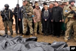 EU Commission President Ursula von der Leyen, center, looks at covered bodies of killed civilians in Bucha, on the outskirts of Kyiv, Ukraine, April 8, 2022.