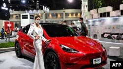 Un modèle fait la promotion de la voiture électrique Tesla Model Y au salon international de l'automobile de Bangkok le 24 mars 2022.