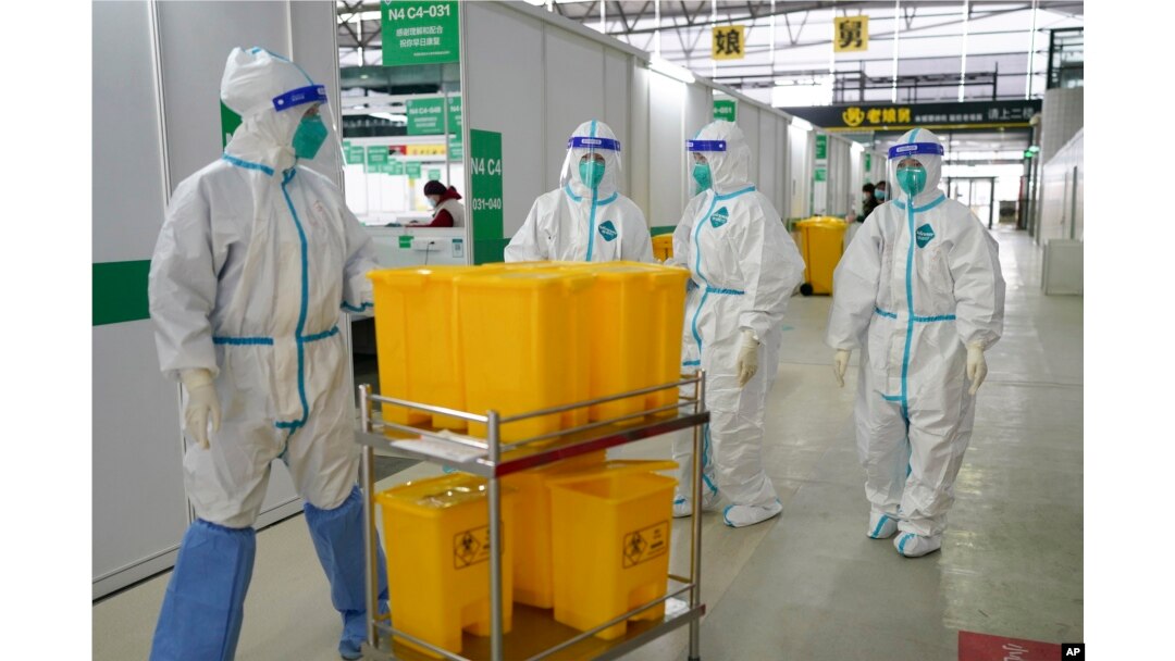 Pekerja medis mengenakan APD bergerak melalui Shanghai New International Expo Center, yang telah diubah menjadi fasilitas karantina untuk pasien COVID-19 dengan gejala ringan atau tanpa gejala, 1 April 2022. (Xinhua via AP)