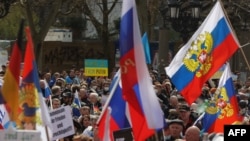 People with Ukrainian flags (background) protest against a pro-Russian march in Frankfurt am Main, western Germany, April 10, 2022.
