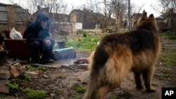 A man warms himself with a fire in the yard of his badly damaged house in Bucha, in the outskirts of Kyiv, Ukraine, April 9, 2022.