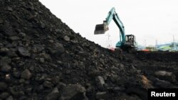 Seorang pekerja mengoperasikan kendaraan berat untuk menurunkan batu bara dari tongkang ke truk, di pelabuhan Karya Citra Nusantara di Jakarta Utara, 13 Januari 2022. (REUTERS/Willy Kurniawan)