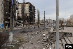 A few residents bike past destroyed apartment blocks in Borodyanka, Ukraine, April 6, 2022. (Heather Murdock/VOA)
