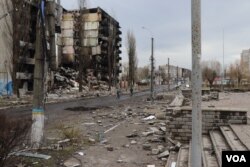 Algunos residentes pasan en bicicleta por bloques de apartamentos destruidos en Borodyanka, Ucrania, el 6 de abril de 2022. [Heather Murdock/VOA]