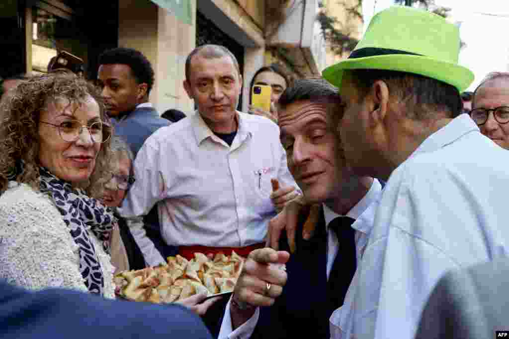 French President Emmanuel Macron is hugged by a man as he talks with the staff of Lebanese Le Chef restaurant during a visit at Beirut's Gemmayze district.