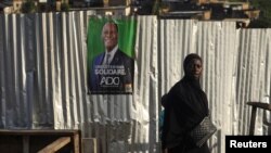 A woman walks past a campaign poster of a presidential candidate Alassane Ouattara of the ruling RHDP coalition, in Attecoube district, Abidjan, Ivory Coast, Oct. 23, 2020. 