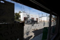 A shop's windows are riddled with bullet holes near City Hall after a gunbattle in Villa Union, Mexico, Dec. 2, 2019.