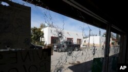 A shop's windows are riddled with bullet holes near City Hall after a gunbattle in Villa Union, Mexico, Dec. 2, 2019. 