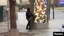 Un policía armado observa uno de los edificios de la Universidad Carolina de Pagra durante un tiroteo el 21 de diciembre de 2023. Foto de redes sociales divulgada por Reuters.