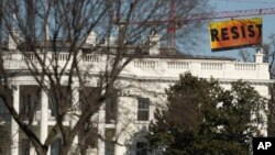 A banner unfurled by Greenpeace demonstrators that reads "Resist" is seen at the construction site of the former Washington Post building, near the White House in Washington, Jan. 25, 2017, after police say protesters climbed a crane at the site refusing to allow workers to work in the area. 