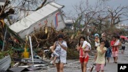 Residents cover their nose from the smell of dead bodies in Tacloban city, Leyte province central Philippines on Sunday, Nov. 10, 2013. 