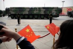 FILE - Spectators wave Chinese flags as military vehicles carrying DF-41 ballistic missiles roll during a parade to commemorate the 70th anniversary of the founding of Communist China in Beijing, Oct. 1, 2019.