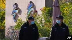 Security guards patrol near the logos for the Beijing Winter Olympics and Paralympics in Beijing, China, Nov. 9, 2021. 