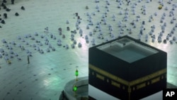 Para jemaah Haji berdoa di depan Ka'bah dengan mengenakan masker dan menjaga jarak di Makkah, Arab Saudi, Minggu, 18 Juli 2021.