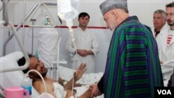 Presiden Afghanistan, Hamid Karzai berbicara dengan seorang korban luka-luka dalam serangan pada hari raya Ashura di Kabul.