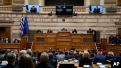 Ukrainian President Volodymyr Zelenskyy, on the screens, addresses the Greek Parliament in Athens, Greece, April 7, 2022.