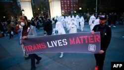 Sejumlah demonstran membawa spanduk bertuliskan "Trans Lives Matter" untuk mengenang para transgender yang tewas dibunuh karena identitasnya dalam sebuah aksi di Washington square park di New York, pada 20 November 2021. (Foto: AFP/Kena Betancur)