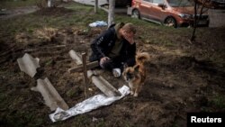 乌克兰布查镇一名男子在埋葬被俄军杀死的朋友后在墓旁悲泣。（2022年4月6日）