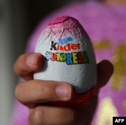 Seorang anak perempuan menunjukkan permen cokelat berbentuk telur Paskah Kinder Surpresa di Santiago, 20 Juni 2016. (MARTIN BERNETTI / AFP)