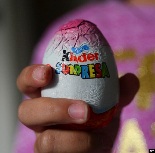 Seorang anak perempuan menunjukkan permen cokelat berbentuk telur Paskah Kinder Surpresa di Santiago, 20 Juni 2016. (MARTIN BERNETTI / AFP)