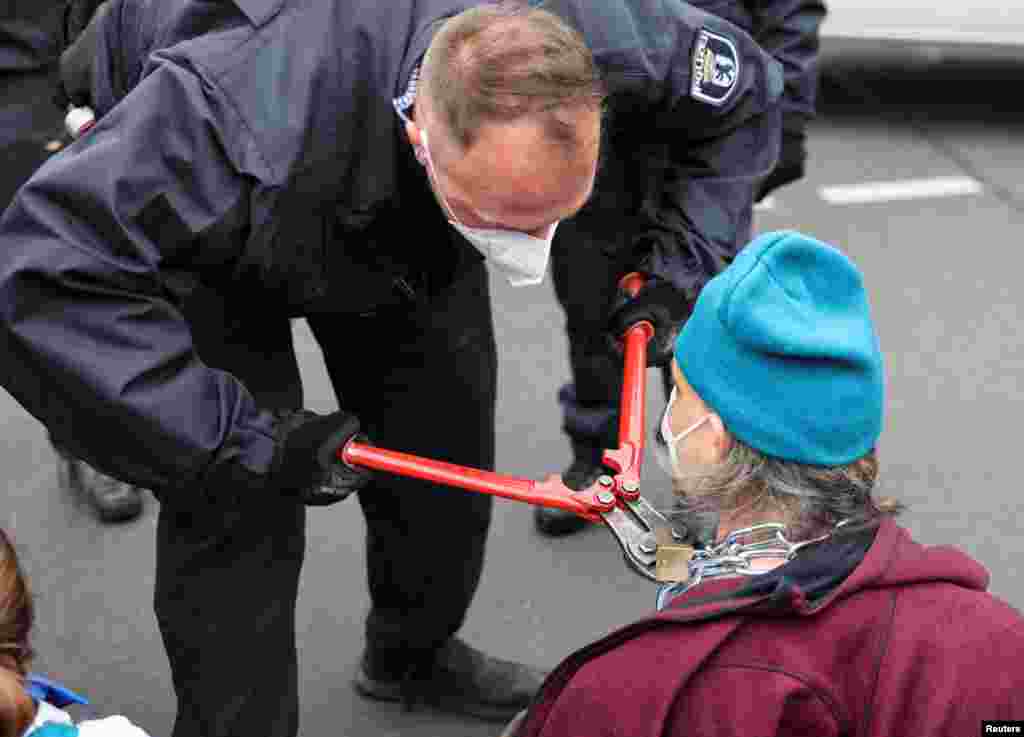 A police removes a chain from an activist from the Scientist Rebellion climate change group blocking a bridge in Berlin, Germany.