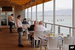 In this June 12, 2020, photo, a server interacts with her customers at a San Francisco. California, restaurant. The hospitality industry has been hard hit by workers quitting their jobs.