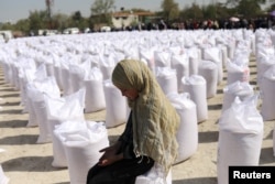 FILE - An Afghan girl waits to receive a rice sack, as part of humanitarian aid sent by China to Afghanistan, at a distribution center in Kabul, Afghanistan, April 7, 2022.