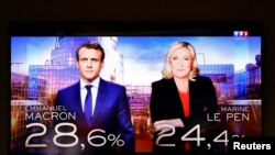 A TV screen shows election results with the two candidates for the second round in the 2022 French presidential election, French President Emmanuel Macron, candidate for his re-election, and Marine Le Pen, leader of French far-right National Rally (Rassem