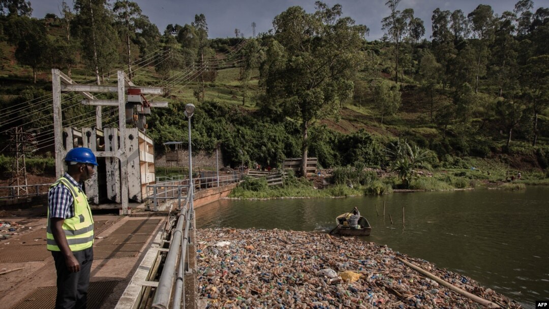 Petugas pembangkit listrik tenaga air Ruzizi 1, mengamati rekannya di atas sampan tengah memeriksa tingkat sampah plastik Sungai Ruzizi di sekitar bendungan di Bukavu, Republik Demokratik Kongo timur, 16 Maret 2022. (Guerchom NDEBO/AFP). 