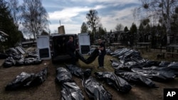 Trabajadores del cementerio descargan cuerpos de civiles muertos desde una camioneta en el cementerio de Bucha, en las afueras de Kiev, Ucrania, el 7 de abril de 2022.