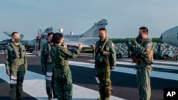 FILE - In this Sept. 15, 2021, file photo released by the Taiwan Presidential Office, Taiwanese President Tsai Ing-wen, center, speaks with military personnel near aircraft parked on a highway in Jiadong, Taiwan.