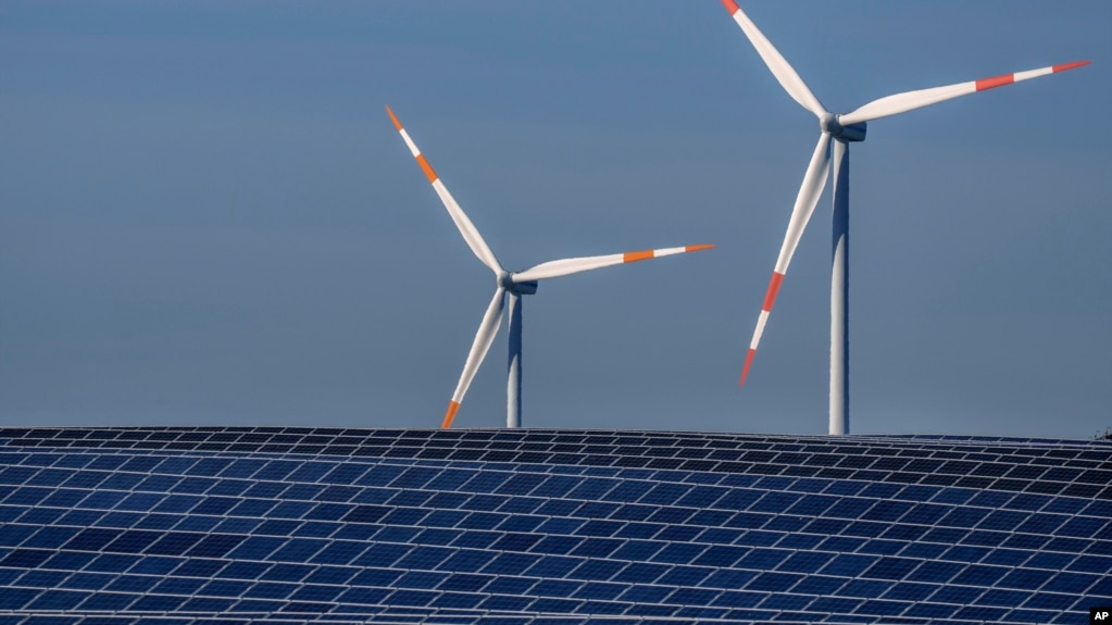 FILE -- Wind turbines turn behind a solar farm in Rapshagen, Germany, Oct. 28, 2021. The German government presented a major package of reforms to boost the construction of renewable power as part of its efforts to meet its climate goals. (AP Photo/Michael Sohn, file)