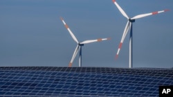 FILE -- Wind turbines turn behind a solar farm in Rapshagen, Germany, Oct. 28, 2021. The German government presented a major package of reforms to boost the construction of renewable power as part of its efforts to meet its climate goals. (AP Photo/Michael Sohn, file)