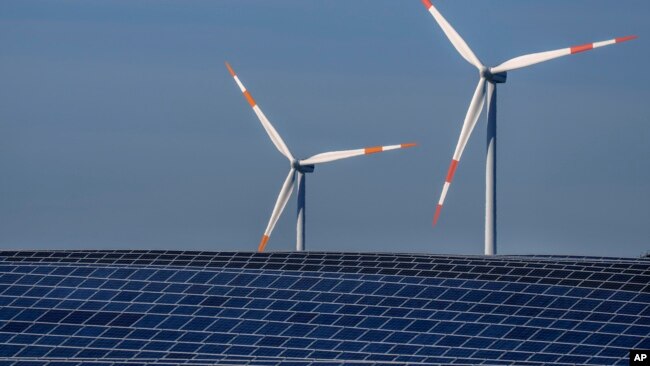 FILE -- Wind turbines turn behind a solar farm in Rapshagen, Germany, Oct. 28, 2021. The German government presented a major package of reforms to boost the construction of renewable power as part of its efforts to meet its climate goals. (AP Photo/Michael Sohn, file)