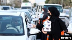 Para sukarelawan di Riyadh, Arab Saudi, membagikan makanan berbuka puasa selama bulan suci Ramadan, 3 April 2022.(REUTERS/Ahmed Yosri)