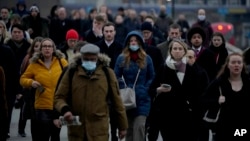 FILE - Workers walk over London Bridge towards the financial district during the morning rush hour in London, Jan. 24, 2022. 