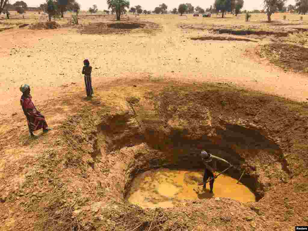 A man digs a pit to obtain water, in a dry river bed, near the village of Tata Bathily in Matam, Senegal.