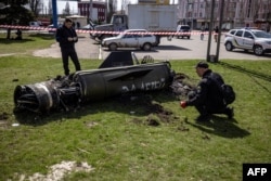 FILE - Ukrainian police inspect the remains of a large rocket with the words "for our children" in Russian next to the main building of a train station in Kramatorsk, eastern Ukraine, April 8, 2022.