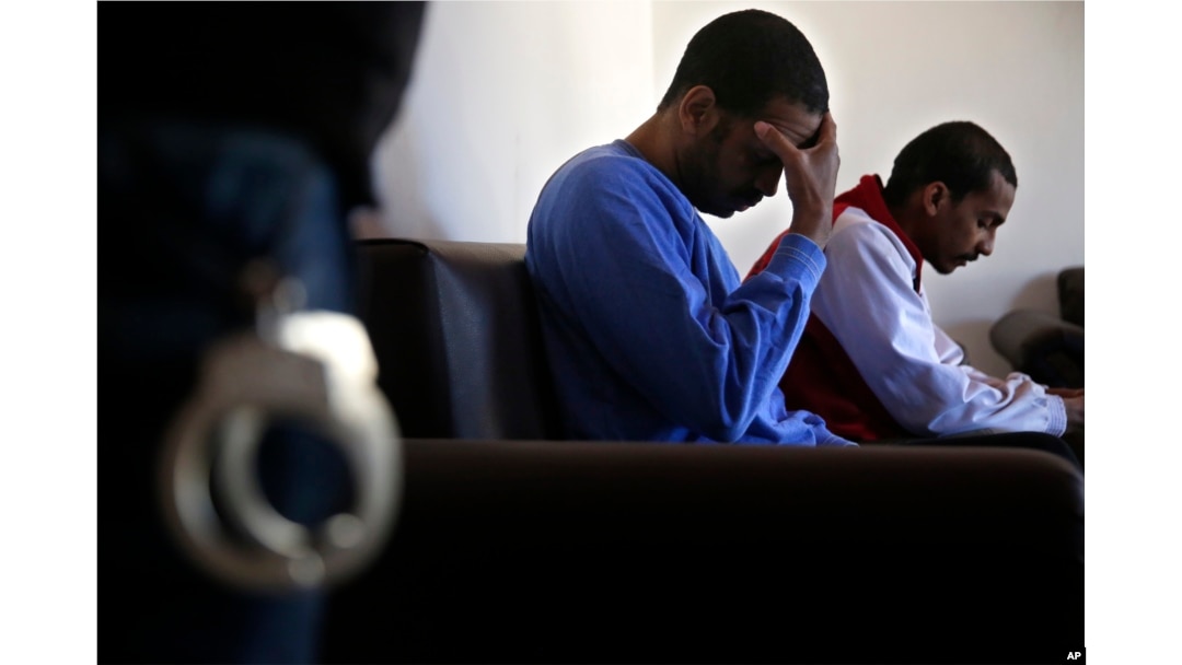 FILE - El Shafee Elsheikh, right, who was allegedly among four British jihadis who made up a brutal Islamic State cell dubbed the "Beatles," sits on a sofa with fellow fighter Alexanda Amon Kotey during an interview at a security center in Kobani, Syria, March 30, 2018.