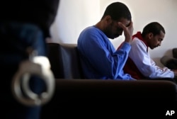 FILE - El Shafee Elsheikh, right, who was allegedly among four British jihadis who made up a brutal Islamic State cell dubbed the "Beatles," sits on a sofa with fellow fighter Alexanda Amon Kotey during an interview at a security center in Kobani, Syria, March 30, 2018.